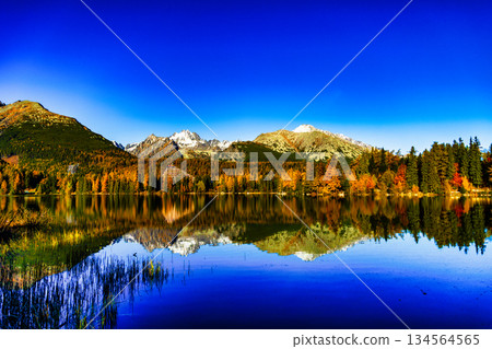 Majestic High Tatra mountains panorama reflected in lake during autumn 134564565