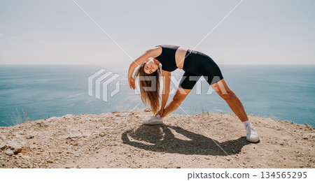 Woman Stretching on Cliffside with Ocean View 134565295