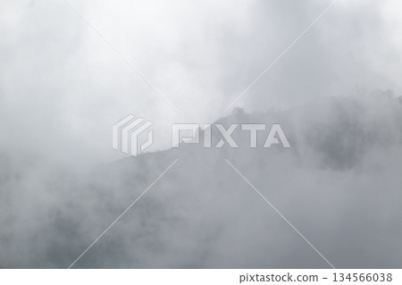 Mountain Ridge Obscured by Thick Gray Fog and Clouds Atmospheric Weather Background Mountain Ridge Obscured by Thick Gray Fog and Clouds Atmospheric Weather Background 134566038