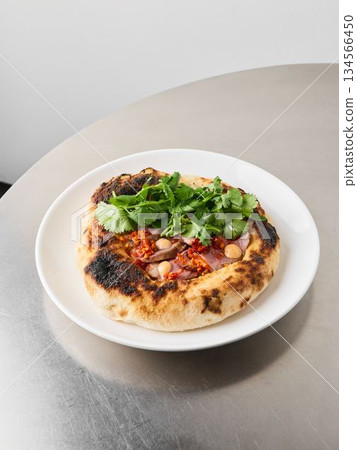 Charred Neapolitan pizza garnished with fresh greens and melted cheese Charred Neapolitan pizza garnished with fresh greens and melted cheese 134566450