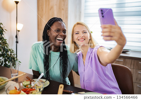 Friends enjoying a joyful meal together while taking selfies Friends enjoying a joyful meal together while taking selfies 134566466