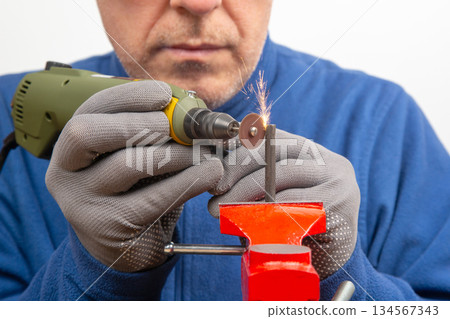 Male locksmith worker processes metal with engraving drill cutting. 134567343