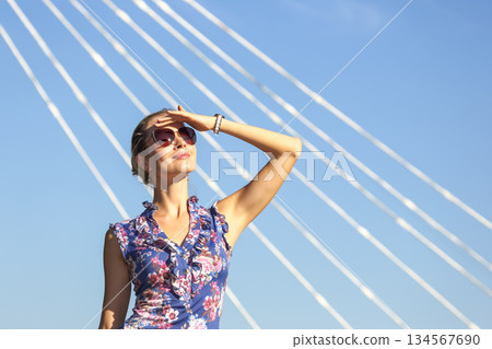 Woman enjoying sunshine with a stylish outfit under a clear blue sky Woman enjoying sunshine with a stylish outfit under a clear blue sky 134567690