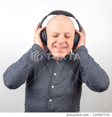 Enjoying music while wearing headphones in a bright setting with a joyful expression Enjoying music while wearing headphones in a bright setting with a joyful expression 134567729