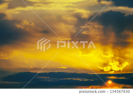 Stunning cloudy sky at dusk with beams of golden sunlight piercing through 134567830