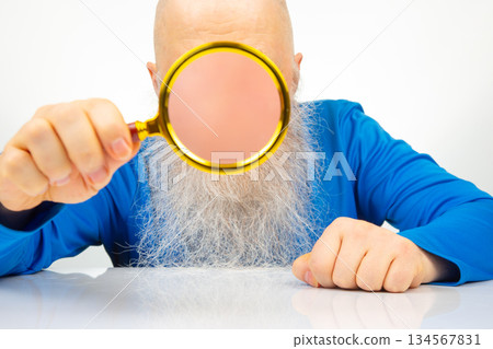 man hides his face with a magnifying glass. The concept of searching for a person in a database 134567831