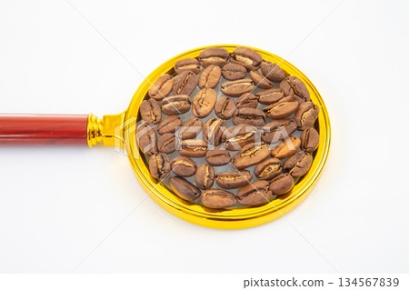 roasted coffee beans on a magnifying glass on a white background. roasted coffee beans on a magnifying glass on a white background. 134567839
