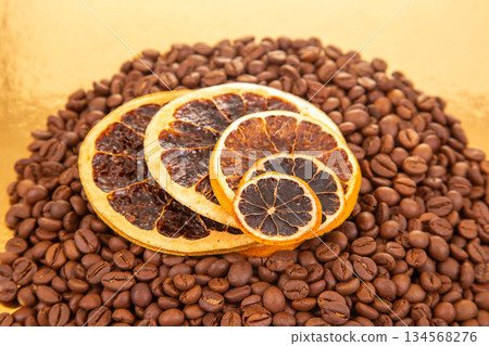 Golden reflective surface hosts coffee beans and dried orange slices Golden reflective surface hosts coffee beans and dried orange slices 134568276