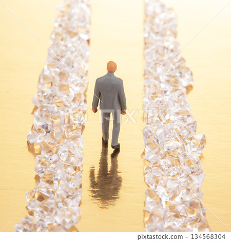 A miniature businessman in a gray suit walks confidently between two rows 134568304
