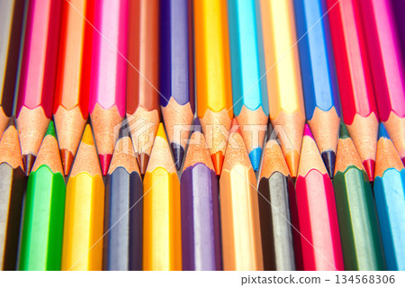 Brightly colored pencils in a layered grid arrangement against a white surface 134568306