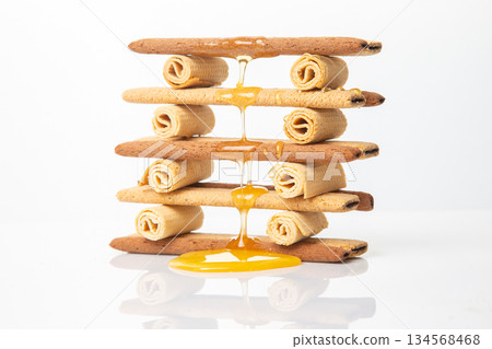Fresh flower honey flows and drips onto herdry crispy cookie sticks. Dessert snack food. 134568468