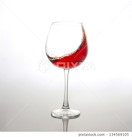 A dramatic splash of red wine captured mid-air, swirling inside a clear wine glass A dramatic splash of red wine captured mid-air, swirling inside a clear wine glass 134569105