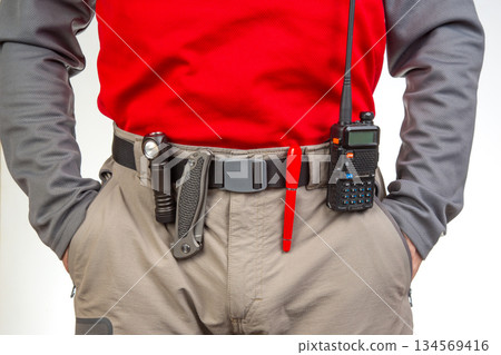 Pen, walkie-talkie, knife and flashlight with clips on the waistband of trekking pants. EDC items 134569416