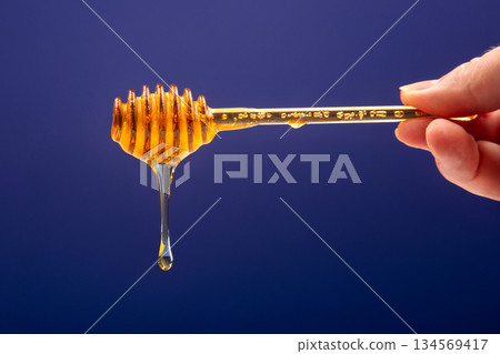 fresh fragrant honey drips from a spoon into a plate on a colored background fresh fragrant honey drips from a spoon into a plate on a colored background 134569417