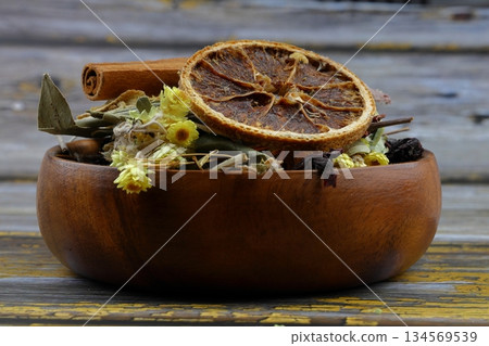 Winter tea for health in cold weather. Flavored with ginger, cinnamon, hibiscus, and orange. Isolated on woodenn background 134569539