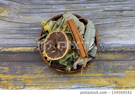 Winter tea for health in cold weather. Flavored with ginger, cinnamon, hibiscus, and orange. Isolated on woodenn background 134569542