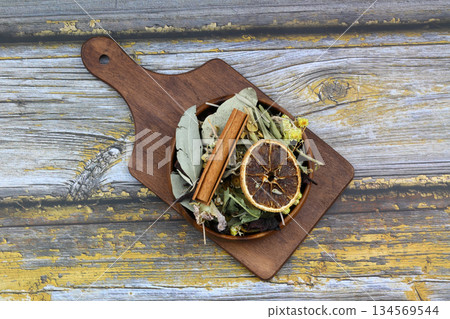 Winter tea for health in cold weather. Flavored with ginger, cinnamon, hibiscus, and orange. Isolated on woodenn background 134569544