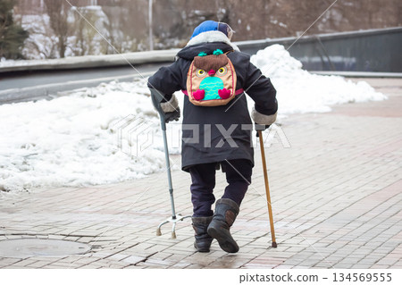 old man with walking sticks walks on a city street old man with walking sticks walks on a city street 134569555