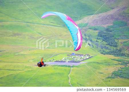 Colorful paraglider soaring above green hills in Iceland's stunning landscape 134569569