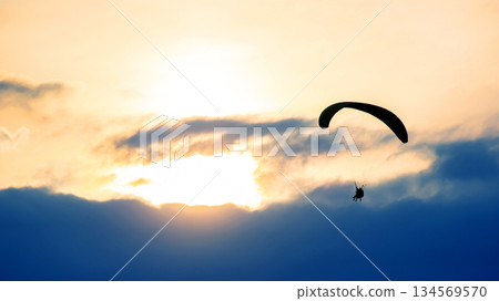 Paraglider soaring above clouds during sunset creates breathtaking view in evening sky 134569570