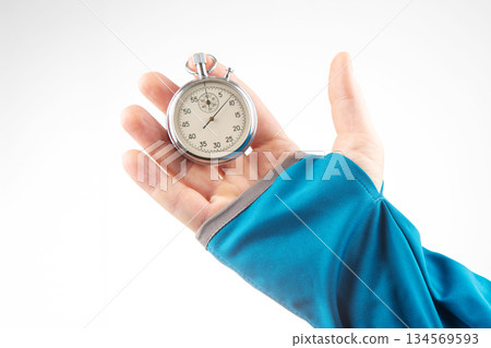 Hand holding silver stopwatch against a bright background in a sporty setting 134569593