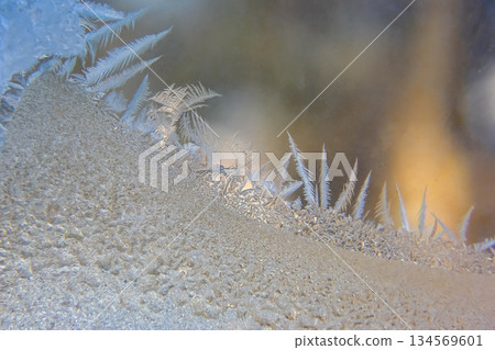 Frost patterns forming intricate designs on a window in winter 134569601