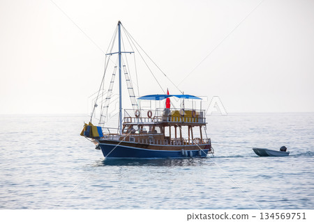 Traditional wooden boat sailing on calm waters near Turkey's coastline during sunrise 134569751