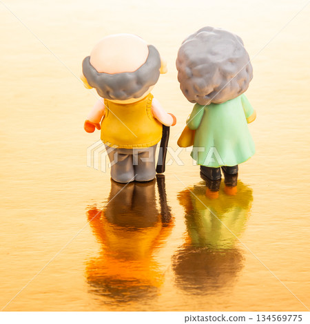 Miniature couple enjoying a peaceful moment by a golden reflective surface Miniature couple enjoying a peaceful moment by a golden reflective surface 134569775