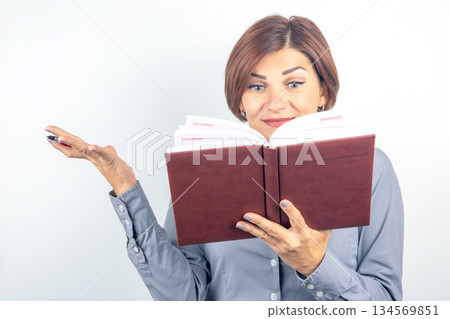 Woman engaging with a book while expressing curiosity in a bright setting Woman engaging with a book while expressing curiosity in a bright setting 134569851