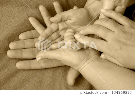 Family hands together in a touching display of love and connection with a newborn's hand Family hands together in a touching display of love and connection with a newborn's hand 134569853