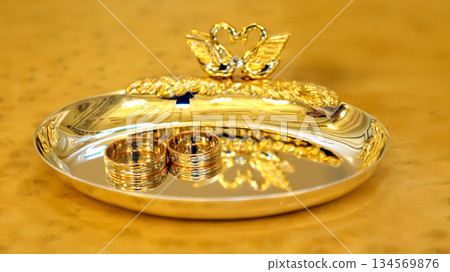 Elegant golden swan ring holder with wedding bands displayed on polished tray Elegant golden swan ring holder with wedding bands displayed on polished tray 134569876