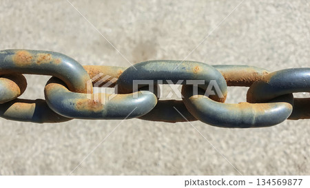 Rusty metal chain links on a surface revealing wear and age under bright sunlight 134569877