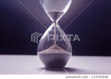 Elegant hourglass captures passage of time against a dark backdrop in soft lighting Elegant hourglass captures passage of time against a dark backdrop in soft lighting 134569886