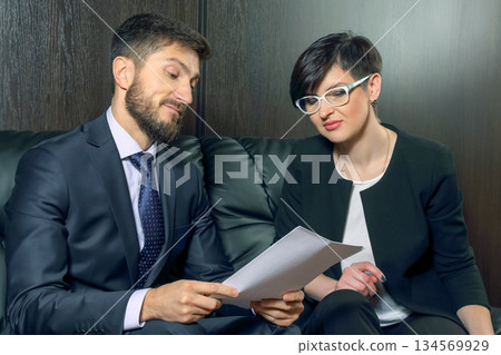 Two professionals reviewing a document in a modern office setting during the daytime Two professionals reviewing a document in a modern office setting during the daytime 134569929