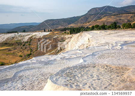 Unique travertine terraces form stunning landscape in Turkey with serene mountains nearby 134569937