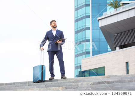 Business man preparing for travel in a modern urban environment with suitcase Business man preparing for travel in a modern urban environment with suitcase 134569971