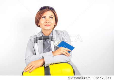 Confident traveler prepares for an adventure with luggage, passport, and money in hand 134570034