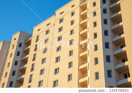 Modern apartment building stands tall against a clear blue sky in the late afternoon Modern apartment building stands tall against a clear blue sky in the late afternoon 134570041