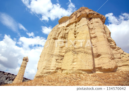 Towering rock formations stand majestically under a vibrant blue sky in Cappadocia, Turkey Towering rock formations stand majestically under a vibrant blue sky in Cappadocia, Turkey 134570042