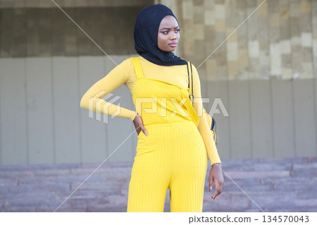 Elegant African woman in yellow outfit poses confidently outdoors in urban setting Elegant African woman in yellow outfit poses confidently outdoors in urban setting 134570043
