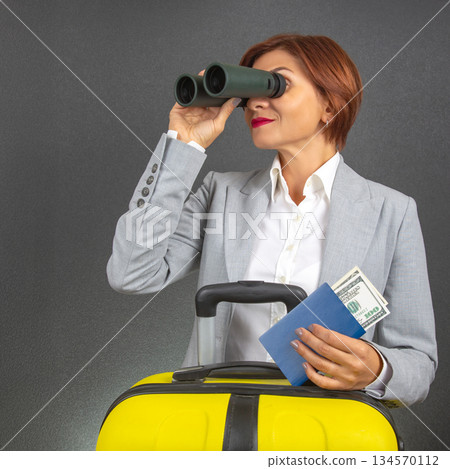 Business traveler using binoculars to spot her flight at the airport 134570112