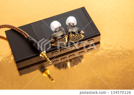 High-quality audio equipment showcased on a reflective golden surface during a product display High-quality audio equipment showcased on a reflective golden surface during a product display 134570126