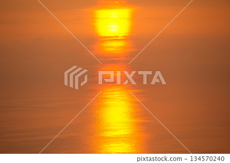 Sunset over calm water reflects golden hues during peaceful evening hours Sunset over calm water reflects golden hues during peaceful evening hours 134570240
