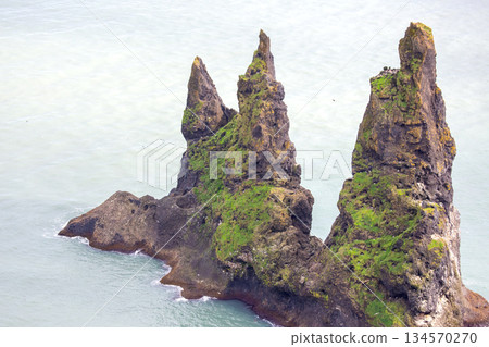 Majestic sea stacks rise above the calm waters in Vik, Iceland during a clear day Majestic sea stacks rise above the calm waters in Vik, Iceland during a clear day 134570270