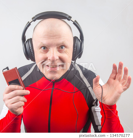 Enthusiastic man in cycling attire enjoying music with headphones and cassette player Enthusiastic man in cycling attire enjoying music with headphones and cassette player 134570277