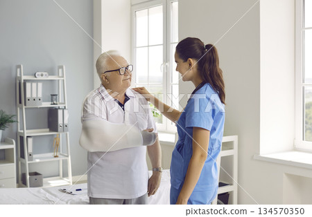 Elderly man with injured arm is discussing treatment with friendly female therapist. 134570350