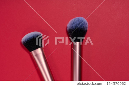 Two makeup brushes with lilac bristles on a red background, top view 134570962