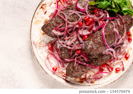 grilled kebabs topped with onions and pomegranate on a white plate in a bright kitchen setting grilled kebabs topped with onions and pomegranate on a white plate in a bright kitchen setting 134570979