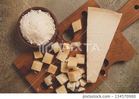 Freshly sliced and grated cheese, parmesan cheese, on a wooden chopping board, rustic style, no people 134570980