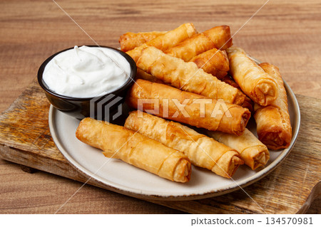 fried spring rolls with cheese, on a wooden background, with cream sauce, no people, 134570981